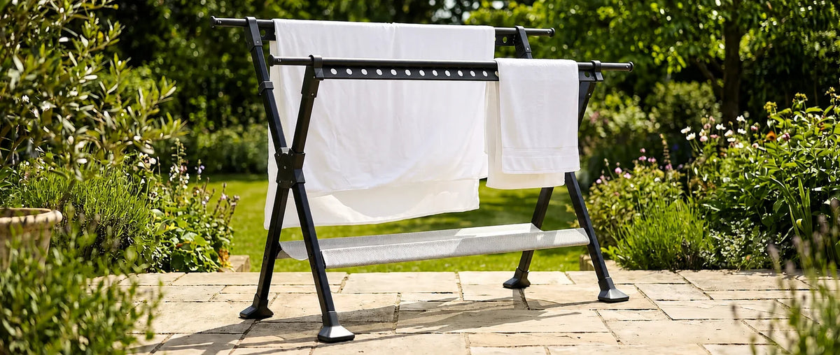 Étendoir à linge extérieur pliable installé sur une terrasse ensoleillée avec du linge blanc en train de sécher